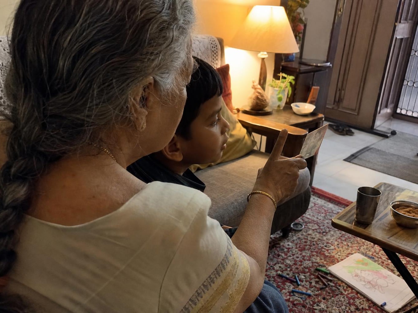 A grandmother showing a restored photograph to her grandchild, seen over her shoulder