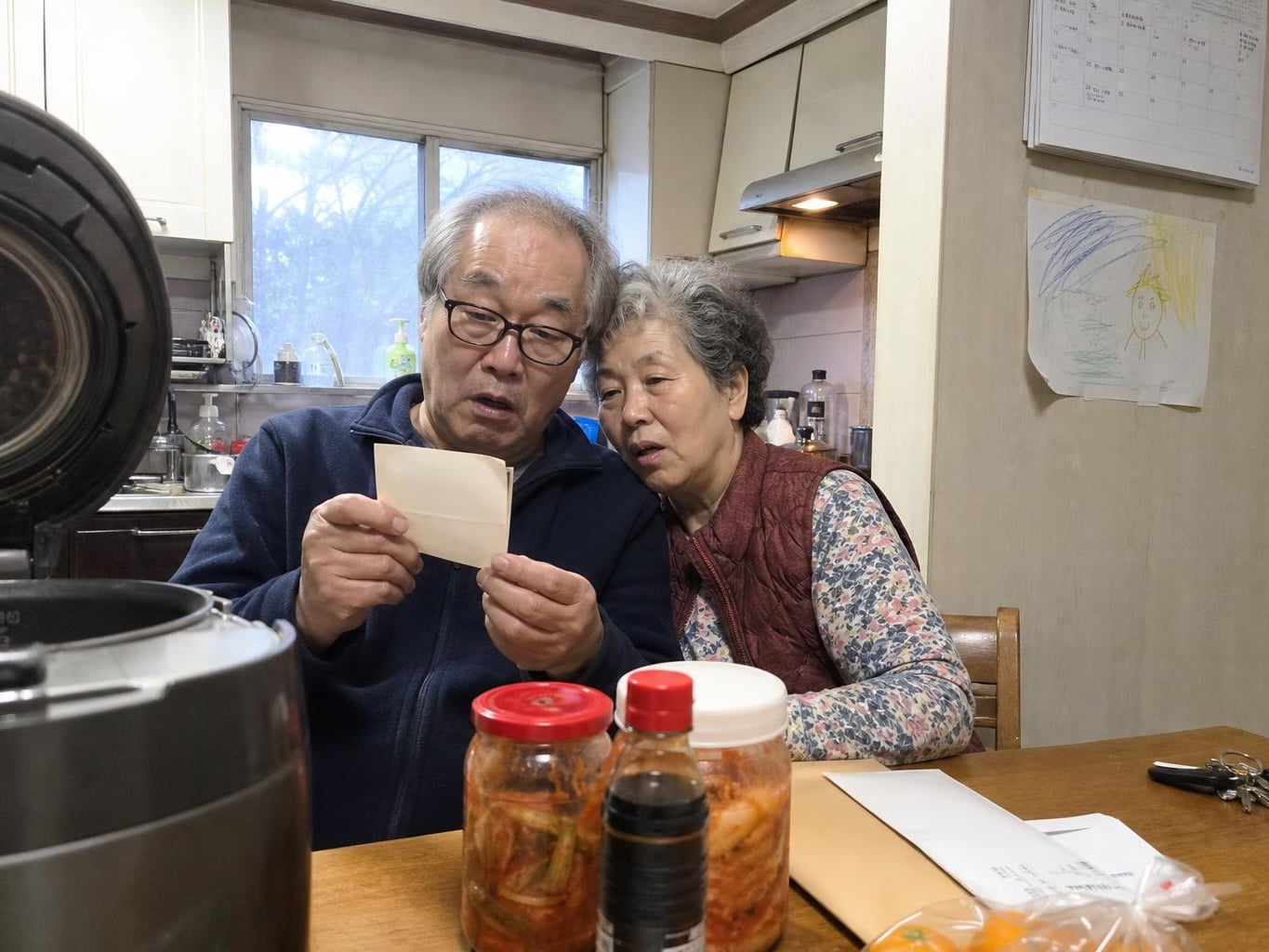 An older couple at their kitchen table looking together at a freshly restored print