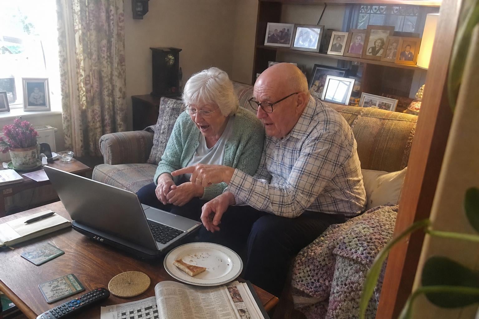 An older couple at a laptop together, delighted as a photo is restored