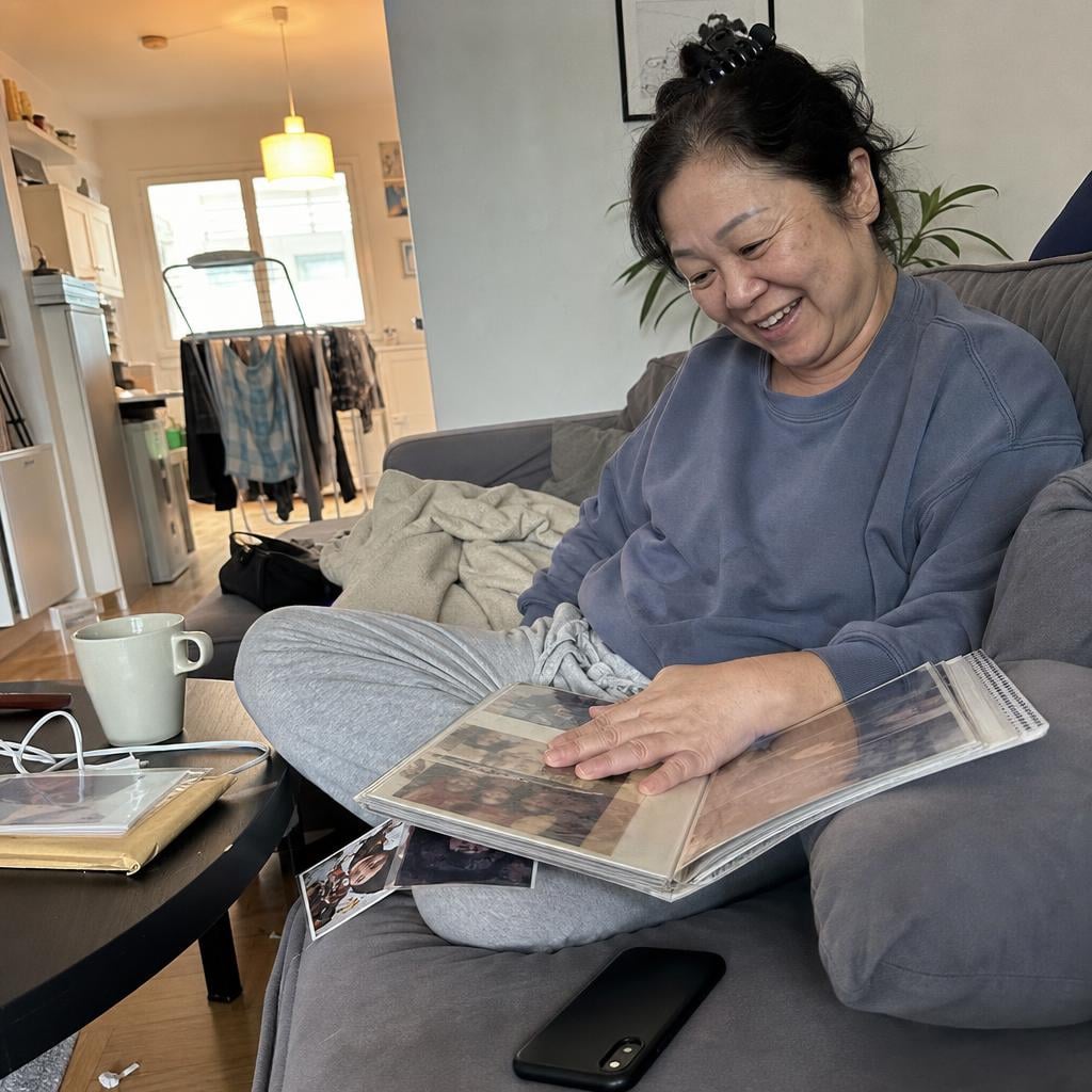 A woman on her couch with an open photo album and her phone